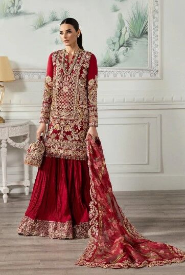 Elegant red and gold Pakistani bridal dress with intricate embroidery, paired with a flowing sharara and a heavily embellished dupatta.