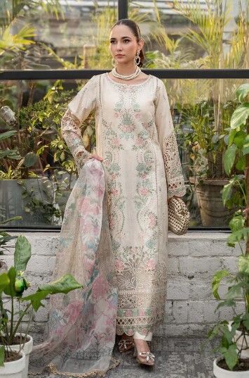 e1 Elegant embroidered beige lawn dress with floral patterns, lace sleeves, and a sheer dupatta, styled with pearl jewelry in a lush green setting.