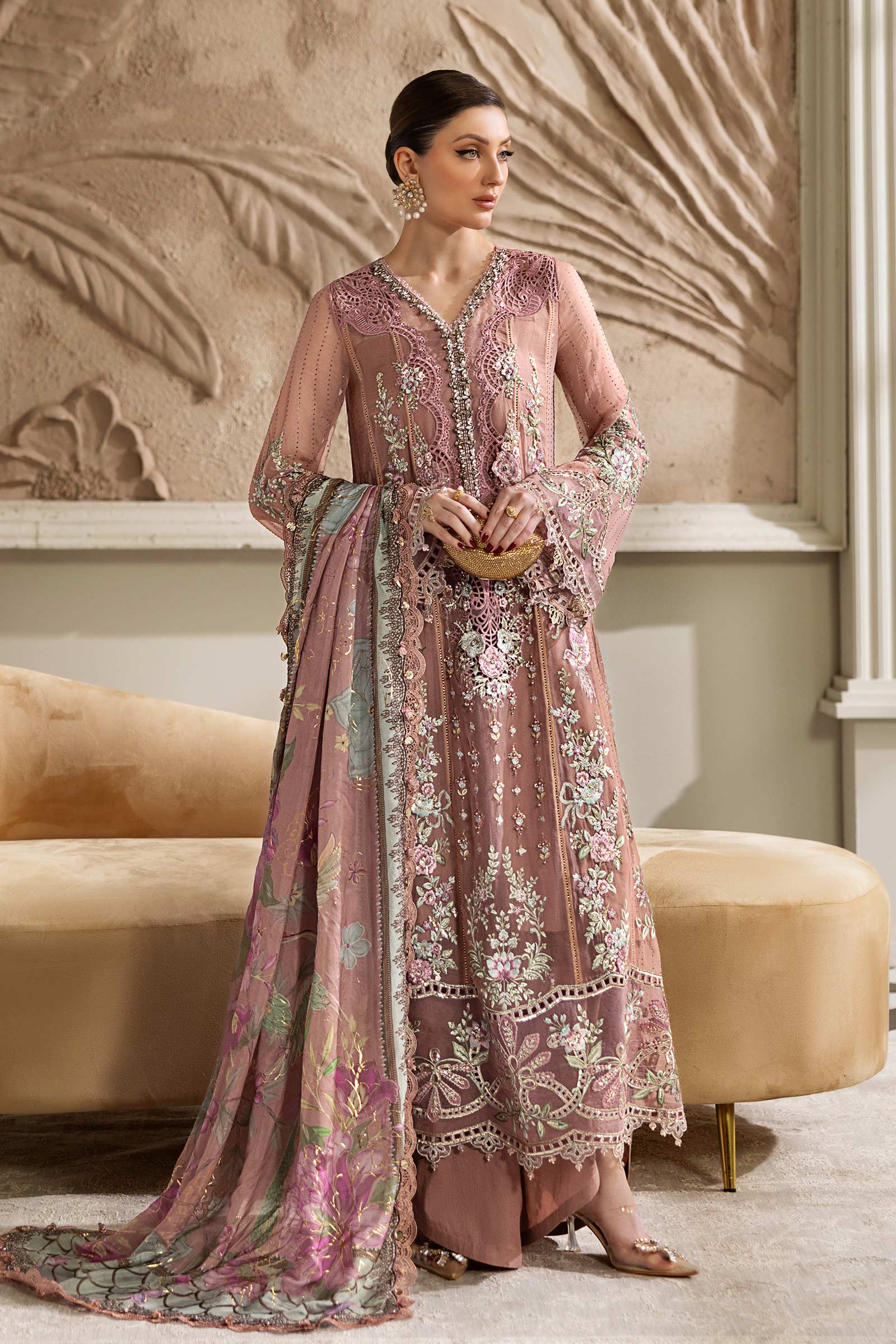 A model wearing a beautiful pink luxury formal dress with intricate floral embroidery and a flowing chiffon dupatta.