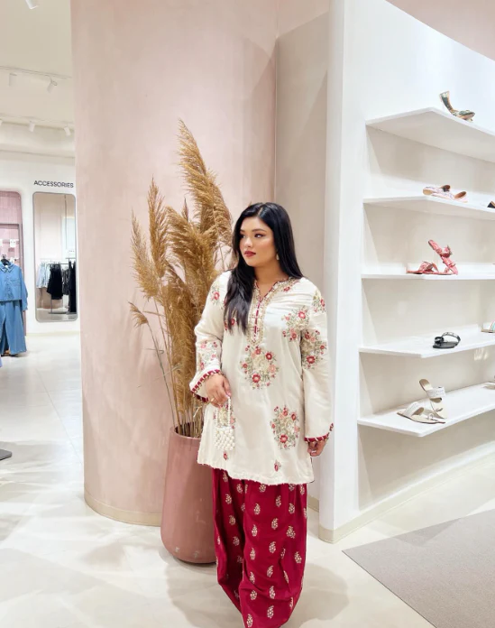 Stylish Ivory Kurta with Red Bottoms for Women Woman wearing ivory embroidered kurta with red trousers in a boutique.