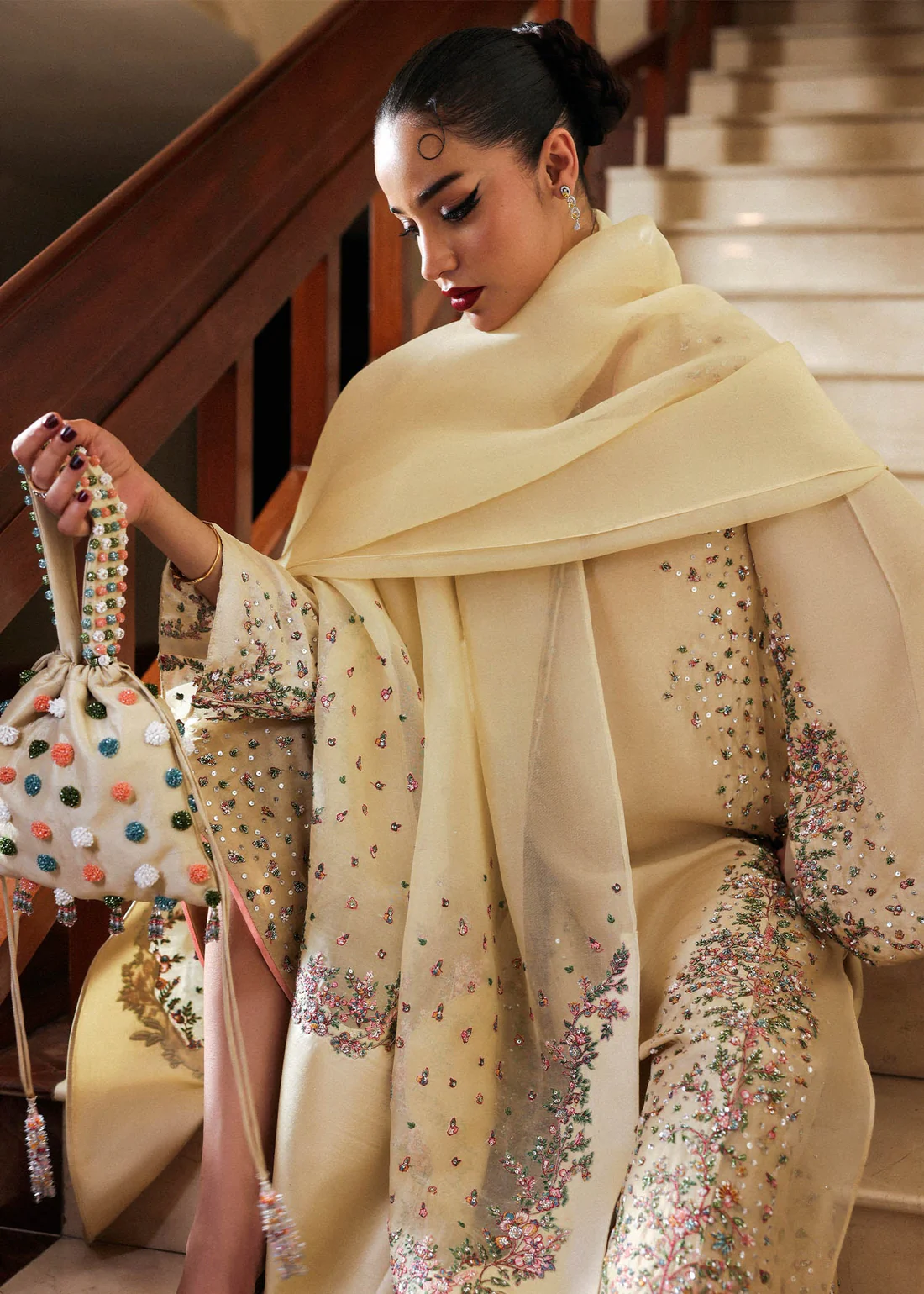 Stylish embroidered attire showcasing traditional craftsmanship. Woman wearing luxury embellished dress with dupatta on staircase.