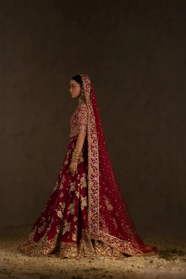 zuria-dor-hot-pink-bridal-lehenga-choli-2 Elegant red wedding dress with detailed gold embroidery and traditional jewelry.